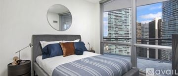 Chicago house for rent - A bedroom with a large bed and a view of the city.