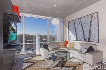 Chicago apartment for rent - A modern living room with a glass table and a large window overlooking a cityscape.