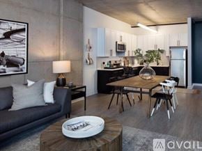Chicago apartment for rent - A modern living room with a grey couch, a wooden coffee table, and a kitchen area in the background.