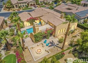 La Quinta house for rent - A house with a pool surrounded by palm trees and a patio area.