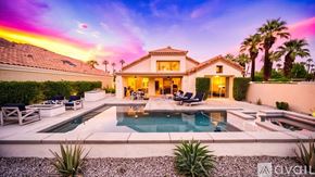 La Quinta house for rent - A house with a pool in the foreground and palm trees in the background.