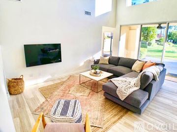 La Quinta house for rent - A living room with a grey couch and a flat screen TV mounted on the wall.