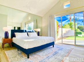 La Quinta house for rent - A bedroom with a large bed and a view of the outdoors through the sliding glass doors.