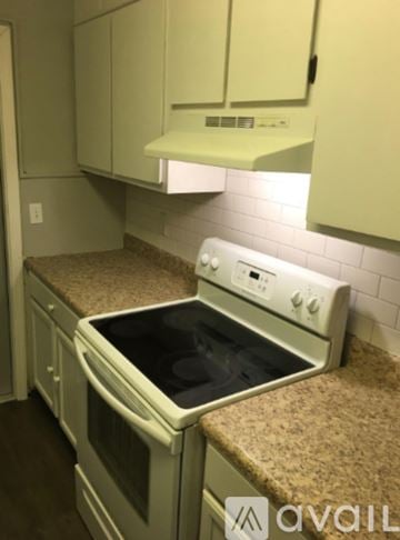 Hinesville apartment for rent - A white oven with a black stove top is in a kitchen with white cabinets.