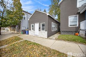 Grand Rapids house for rent - A house with a grey exterior and a white door is surrounded by fallen leaves.