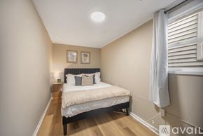 Grand Rapids house for rent - A bedroom with a bed, nightstand, and window with white curtains.