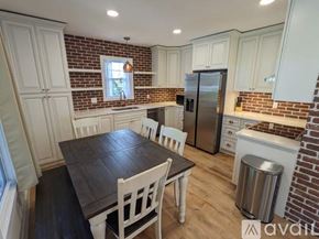 Asheville apartment for rent - A kitchen with a table and chairs in the foreground and a brick wall above the counter.