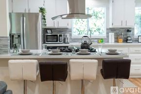 Fullerton house for rent - A modern kitchen with white cabinets and a central island with a sink and a microwave.