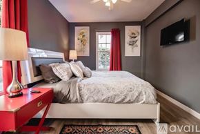 Los Angeles house for rent - A bedroom with a bed, a red side table, and a television mounted on the wall.