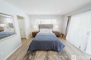North Hollywood townhouse for rent - A bedroom with a large bed and a mirror on the wall.