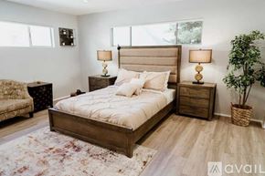 North Hollywood townhouse for rent - A bedroom with a large bed, two lamps, and a potted plant.