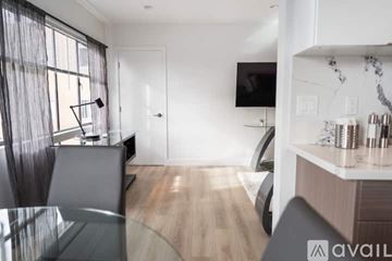 North Hollywood apartment for rent - A modern living room with a glass table and a television on the wall.
