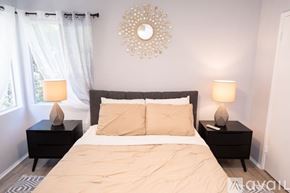 Los Angeles apartment for rent - A bedroom with a large bed, two nightstands with lamps, and a decorative wall mirror.