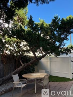 North Hollywood apartment for rent - A patio with a table and chairs is surrounded by a white fence and trees.