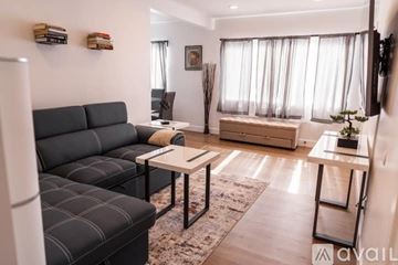 North Hollywood apartment for rent - A living room with a black sofa and a glass table.