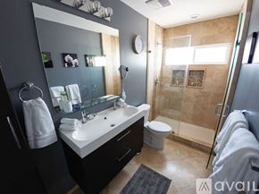 Los Angeles house for rent - A bathroom with a white sink, toilet, and a glass shower stall.