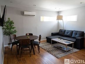Los Angeles house for rent - A living room with a black couch, a wooden table, and a glass coffee table.