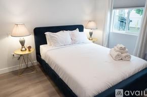 Los Angeles house for rent - A bedroom with a large bed, two lamps, and a small table with a lamp on it.
