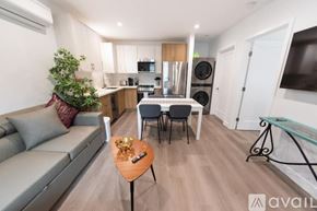 Los Angeles house for rent - A modern living room with a grey sofa, a wooden coffee table, and a glass table.