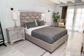 Los Angeles house for rent - A bedroom with a large bed and a wooden floor.