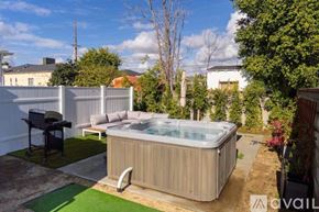 Los Angeles house for rent - A hot tub is in the middle of a backyard with a patio and a grill.