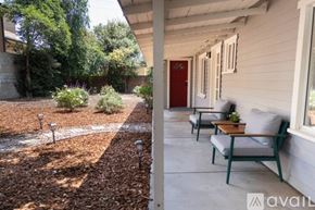 Glendale house for rent - A patio with a table and chairs is surrounded by a gravel area and trees.