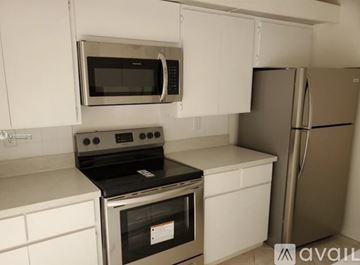 West Palm Beach house for rent - A kitchen with a stove, microwave, and refrigerator.