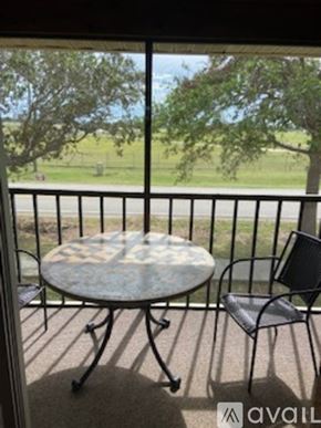 Venice condo for rent - A patio with a table and chairs overlooking a grassy field.