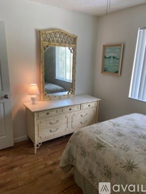 Venice condo for rent - A bedroom with a bed, a dresser with a mirror and a painting on the wall.