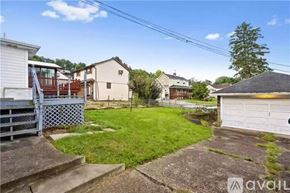 Belle Vernon house for rent - A backyard with a white house, a green lawn, and a white garage.