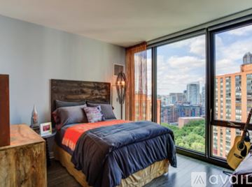 Chicago apartment for rent - A bedroom with a large bed and a view of the city.
