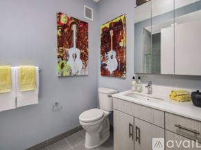 Chicago apartment for rent - A bathroom with a white toilet and a painting of a guitar on the wall.