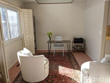 Minnetonka house for rent - A living room with a white chair, a white sofa, and a small table with a vase of flowers on it.