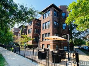 Chicago apartment for rent - A large brick building with a black fence in front.