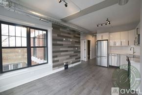 Chicago apartment for rent - A spacious room with a grey wall and a window overlooking a building.