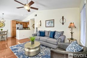 Oceanside apartment for rent - A living room with a grey couch, a round coffee table, and a ceiling fan.