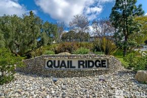 Oceanside apartment for rent - A stone sign that says Quail Ridge in front of some trees.