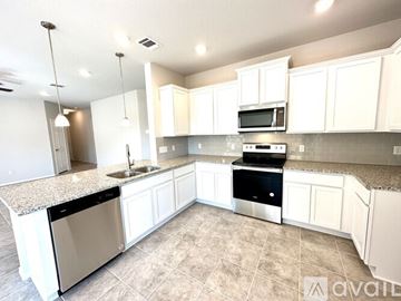 Temple house for rent - A kitchen with white cabinets and a granite countertop.