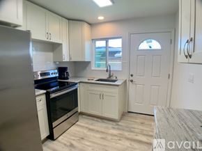 Kailua house for rent - A kitchen with white cabinets and a stainless steel refrigerator.