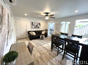 Kailua house for rent - A living room with a black couch and a dining table with chairs.