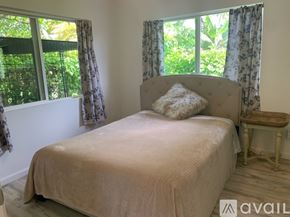Kailua house for rent - A bedroom with a bed, a small table, and a window with curtains.