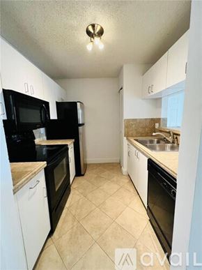West Palm Beach condo for rent - A kitchen with black and white appliances and a tiled floor.