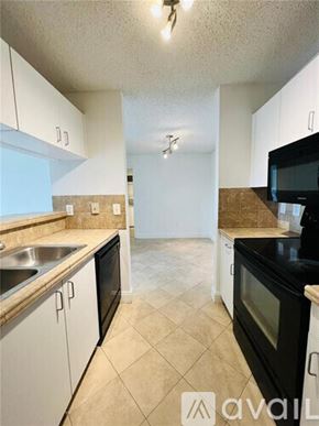 West Palm Beach condo for rent - A kitchen with black appliances and white cabinets.