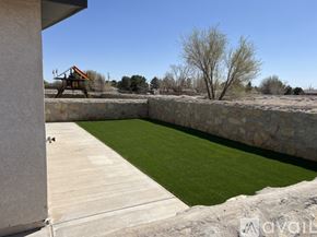 Socorro apartment for rent - A backyard with a stone wall and a green lawn.