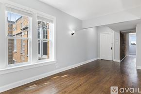 Chicago apartment for rent - A room with wooden floors and white walls, with a window showing a building outside.