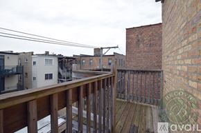 Chicago apartment for rent - A balcony with a wooden railing overlooks a brick building and a snow-covered ground.