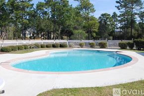 Southport condo for rent - A round above ground pool surrounded by a white fence and green trees.
