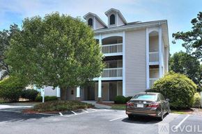 Southport condo for rent - A car is parked in front of a two-story building.