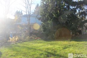 Brooktondale apartment for rent - A house with a blue roof is surrounded by trees and grass.