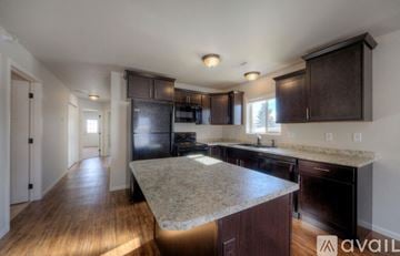 Rapid City apartment for rent - A kitchen with dark wood cabinets and a granite countertop.